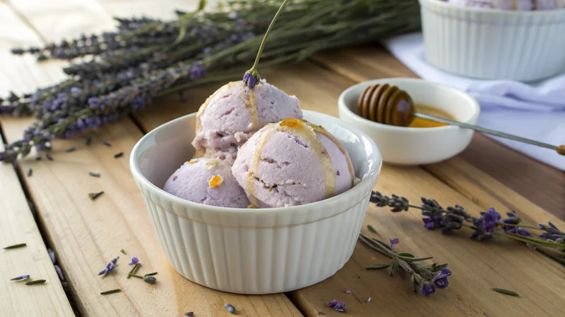 Close-up of a single scoop of honey lavender ice cream in a small ceramic dish, honey drip catching the light, fresh lavender sprig garnish, magazine quality