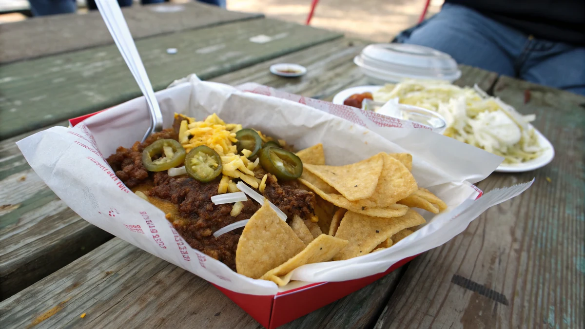 Texas Frito Pie in a slit-open Fritos bag with no-bean chili, shredded cheddar, diced white onion, and pickled jalapenos