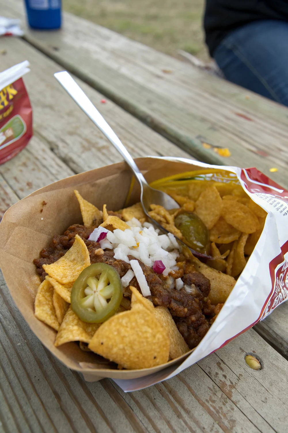 Vertical view of Texas Frito Pie eaten straight from the bag, save this San Antonio cafeteria classic with no-bean chili recipe