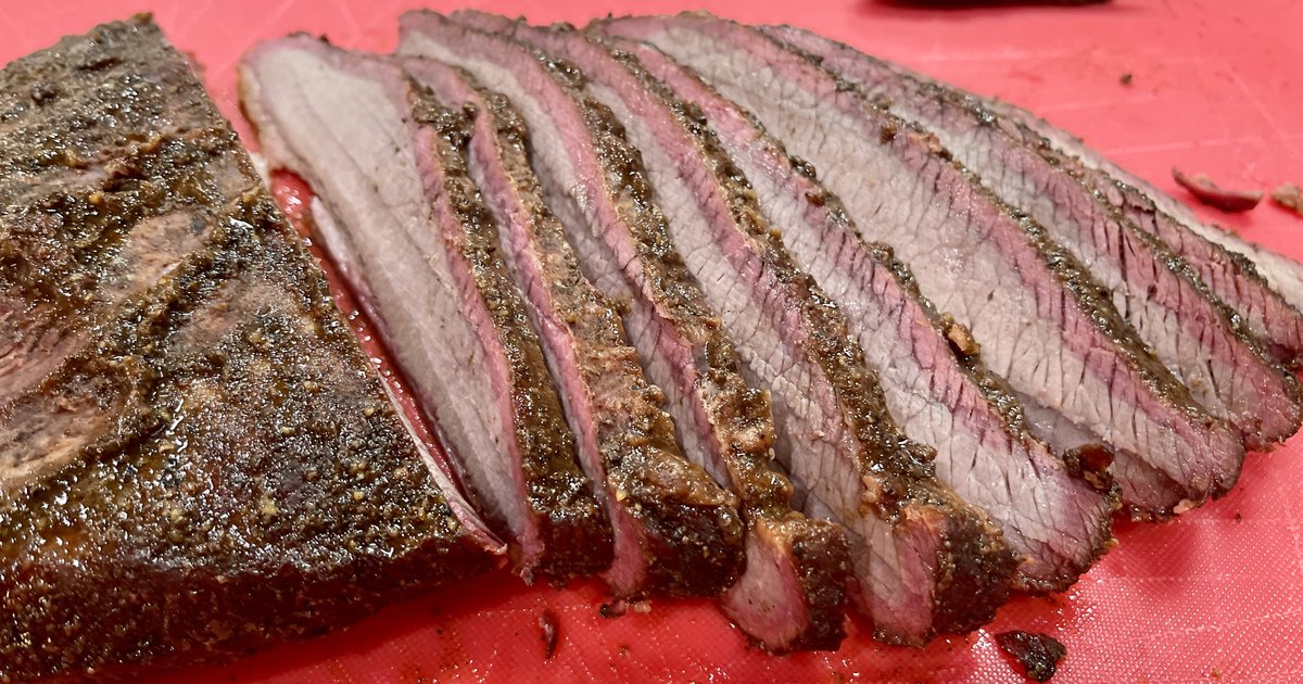 Sliced smoked Texas BBQ brisket showing deep pink smoke ring on a red cutting board